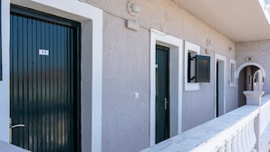 A building facade with numbered doors, a marble balcony, and a textured wall. - Bed and Breakfast 'The Kavos Sandy Inn-Double Room' with Shared Pool, Wi-Fi and Air Conditioning (Kavos)