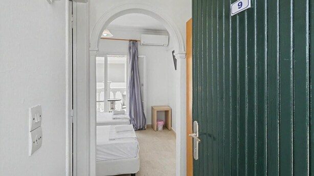 A narrow hallway leading to a bedroom with a bed, a small table, and a curtain. - Bed and Breakfast 'The Kavos Sandy Inn-Double Room' with Shared Pool, Wi-Fi and Air Conditioning (Kavos)