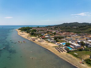 Une vue aérienne d’une ville côtière, avec une plage, des bateaux et différents types de bâtiments.