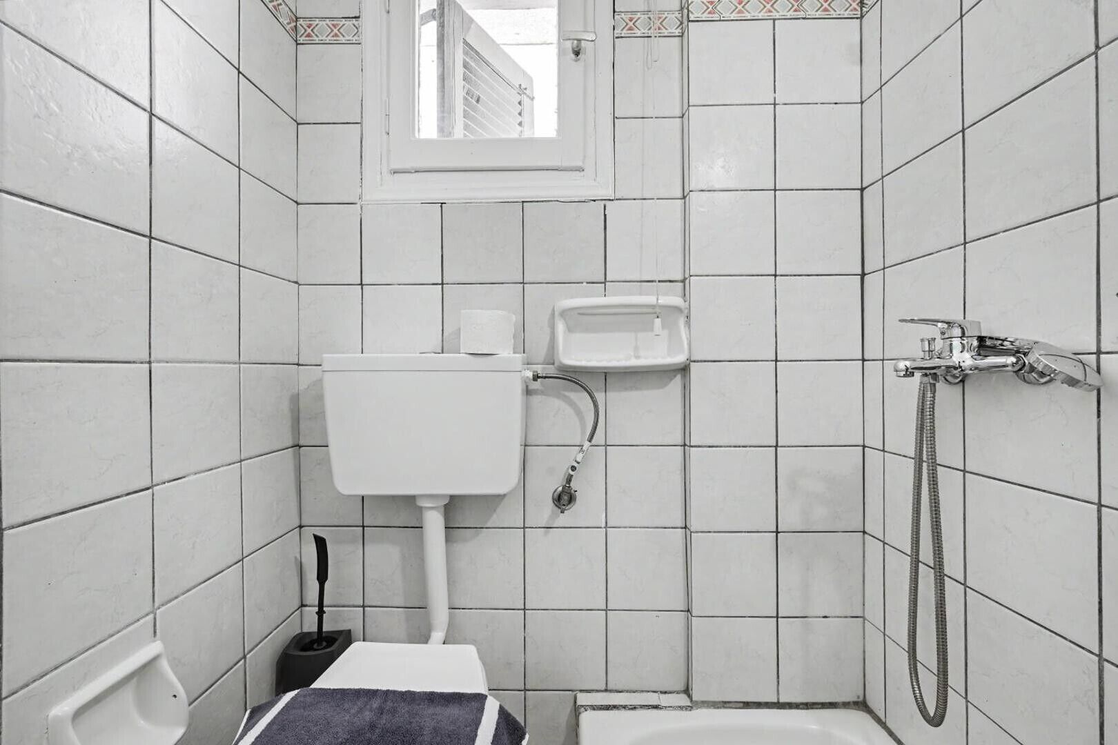 A small, tiled bathroom with a toilet, bidet, and shower.