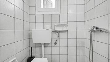 A small, tiled bathroom with a toilet, bidet, and shower.