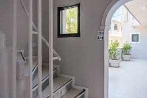 A staircase leading to a landing with a small window and a door with a sign above it.