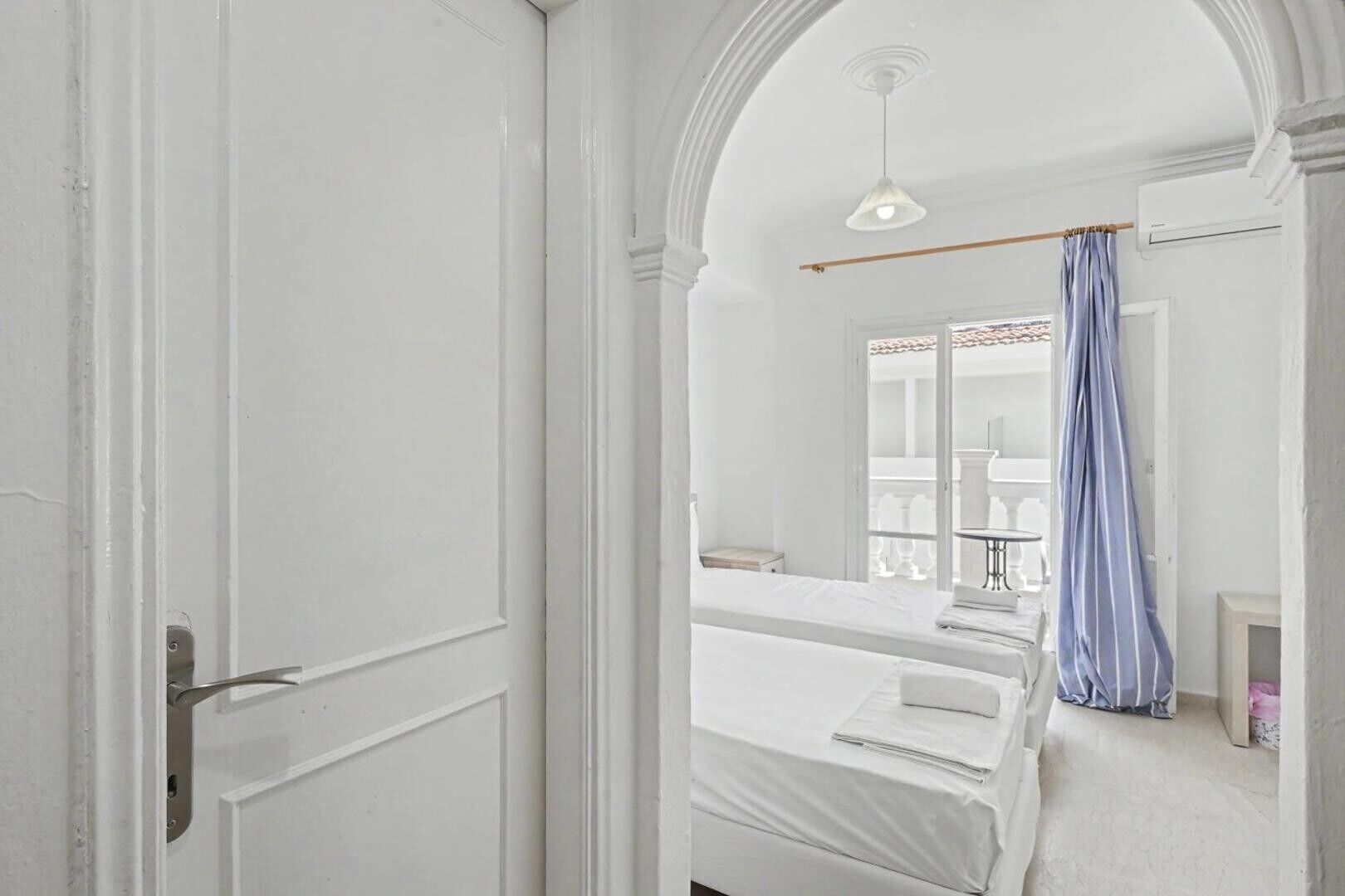 Une chambre d’hôtel avec un lit, une fenêtre donnant sur un paysage agréable et une porte.