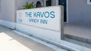 Skilt for 'The Kavos Sandvly Inn' med logo, tekst og bygningens indgang.