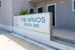 A sign for 'The Kavos Sandvly Inn' with a simple design and a clear view of the building's entrance.
