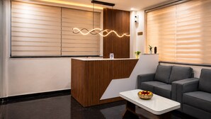 A reception area with a wooden reception desk, a white table, and a grey sofa.