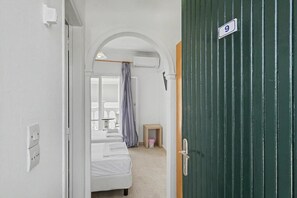 A narrow hallway leading to a bedroom with a bed, a small table, and a curtain. - Bed and Breakfast 'The Kavos Sandy Inn-Double Room' with Shared Pool, Wi-Fi and Air Conditioning (Kavos)