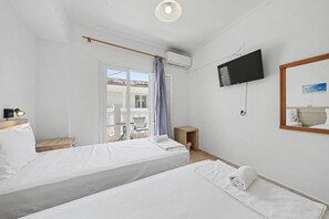 A hotel room with two beds, a TV, a small table, and a balcony with a chair. - Bed and Breakfast 'The Kavos Sandy Inn-Double Room' with Shared Pool, Wi-Fi and Air Conditioning (Kavos)