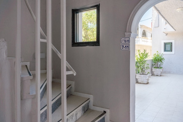 A staircase leading to a landing with a small window and a door marked with a number.