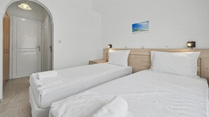 A hotel room with two beds, a wooden headboard, a small bedside table with a lamp, and a picture on the wall. - Bed and Breakfast 'The Kavos Sandy Inn-Double Room' with Shared Pool, Wi-Fi and Air Conditioning (Kavos)