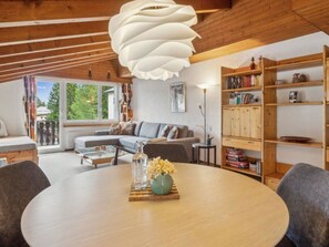 A cozy living room with a round wooden table, a sofa, and a bookshelf. - A301 Appartement/Fewo,   Ferienwohnung A301 IH by Interhome (Lenzerheide)