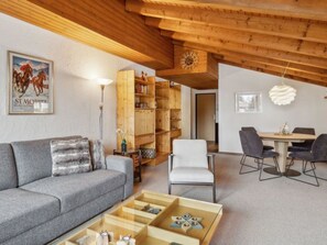 A modern living room with a sofa, a coffee table, a bookshelf, and a dining area with chairs. - A301 Appartement/Fewo,   Ferienwohnung A301 IH by Interhome (Lenzerheide)