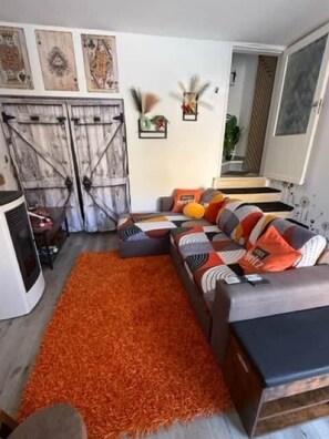 Un saló amb un sofà modular, una catifa taronja i obra d'art decorativa a la paret.