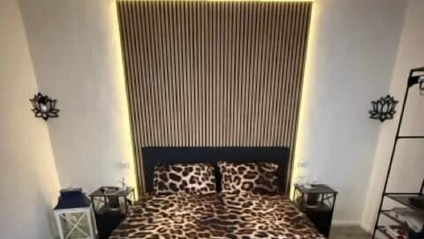 Een slaapkamer met een bed, hoofdeinde en een wandlamp.