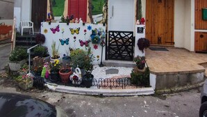Een huis met een muurschildering van een landschap, een witte deur en een kleine tuin met planten in potten.