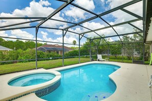 A swimming pool with a hot tub, surrounded by a covered area with a metal frame, and a view of a house in the background. - Near Disney & Top Attractions! Poolside Oasis (Davenport)