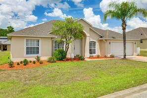 A residential house with a front yard, a garage, and a well-maintained lawn. - Near Disney & Top Attractions! Poolside Oasis (Davenport)