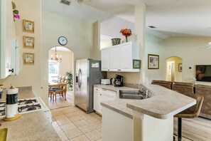 A modern kitchen with a central island, built-in appliances, and a dining area with a chandelier. - Near Disney & Top Attractions! Poolside Oasis (Davenport)