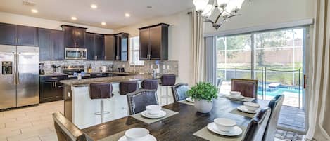 A modern kitchen with dark cabinets, stainless steel appliances, and a large island with bar stools.