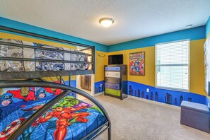 A bunk bed with superhero-themed bedding, a window with blinds, and a wall with comic book art. - Private Pool & Game Room! Championsgate Resort Gem (Davenport)