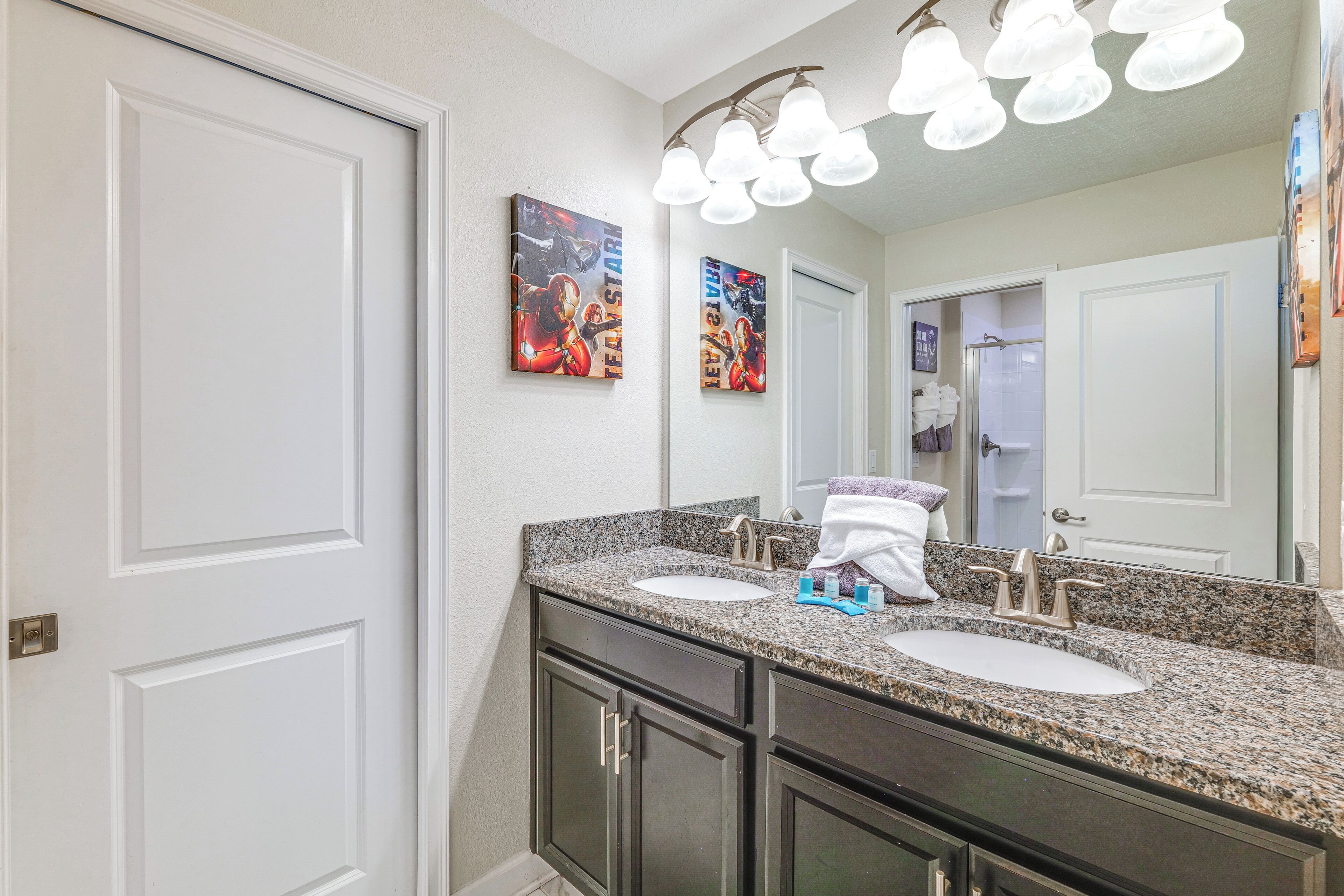 A bathroom with two sinks, a mirror, and artwork on the wall.