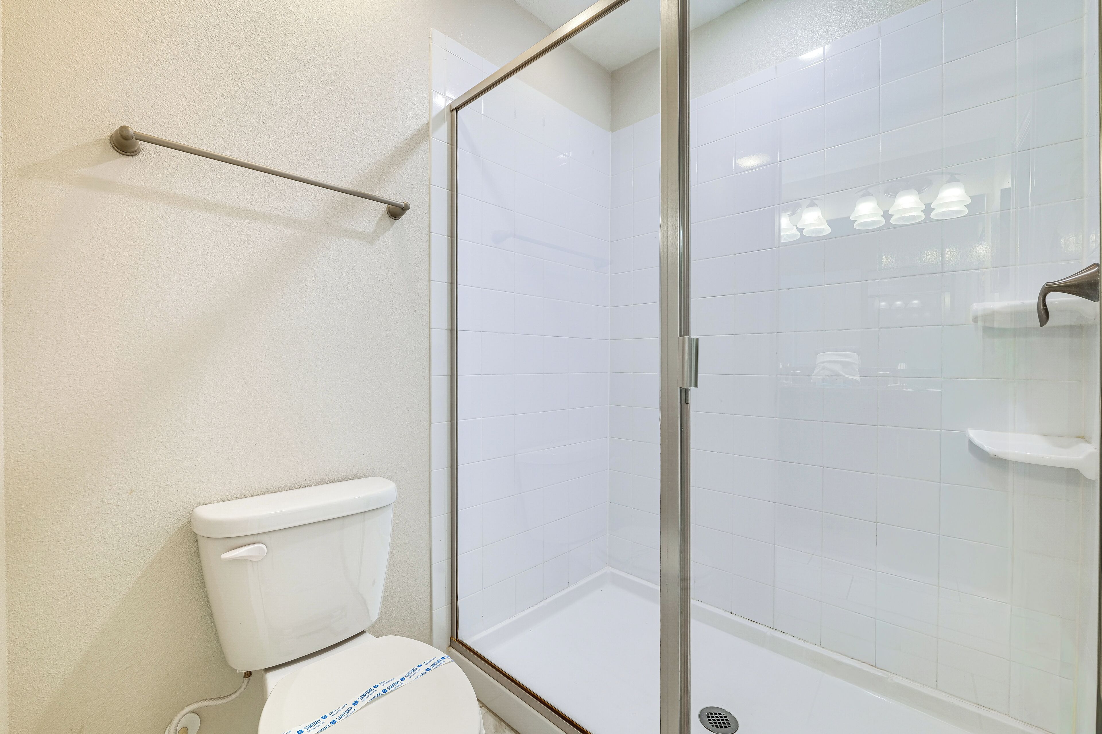 Une salle de bain équipée de toilettes, d’une douche à parois de verre et d’un porte-serviettes.