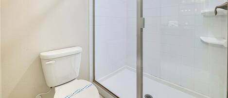 Une salle de bain équipée de toilettes, d’une douche à parois de verre et d’un porte-serviettes.