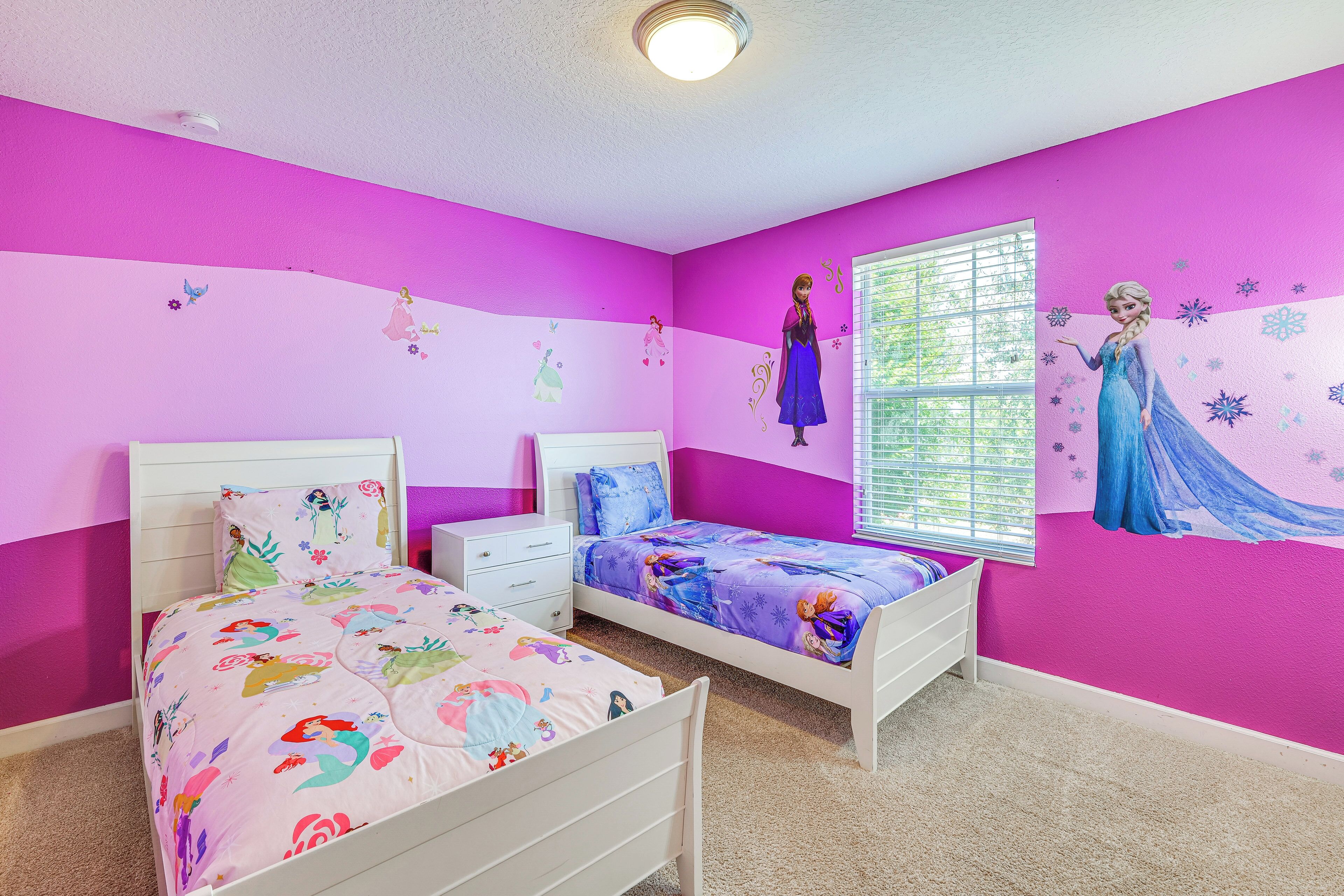 A bedroom with two beds, a window, and wall decorations.