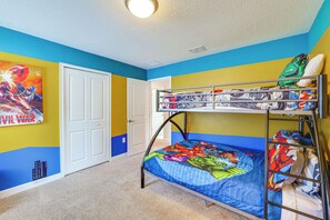 Ein Stockbett mit einem Superhelden-Bettbezug, eine Tür und eine Wand mit einem Wandgemälde im Comic-Stil.