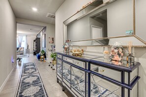 A hallway with a decorative console table, a large mirror, and a patterned rug. - At Home Away From Home in Zhills (Zephyrhills)