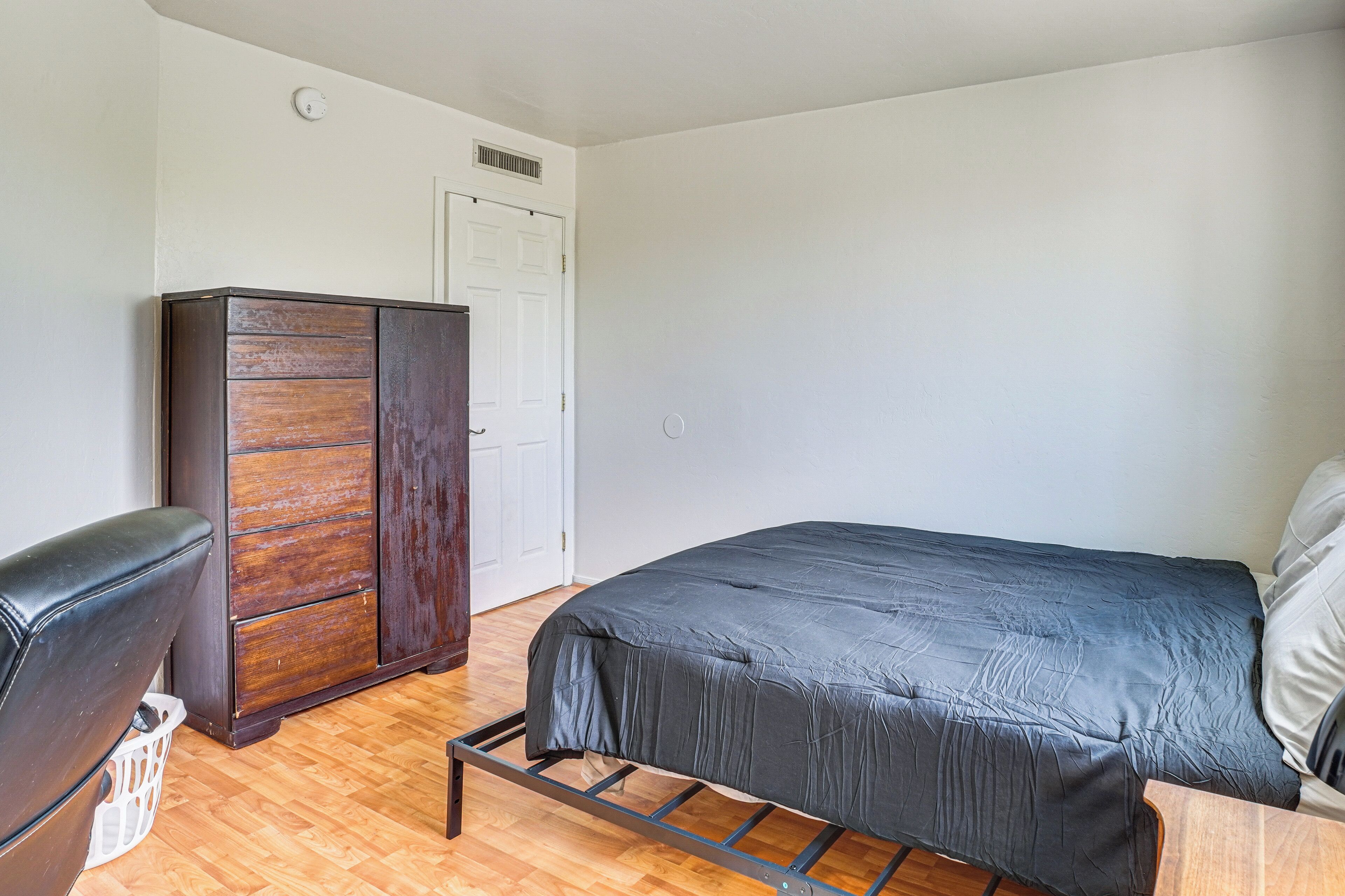 Un dormitorio con cama, armario y silla.