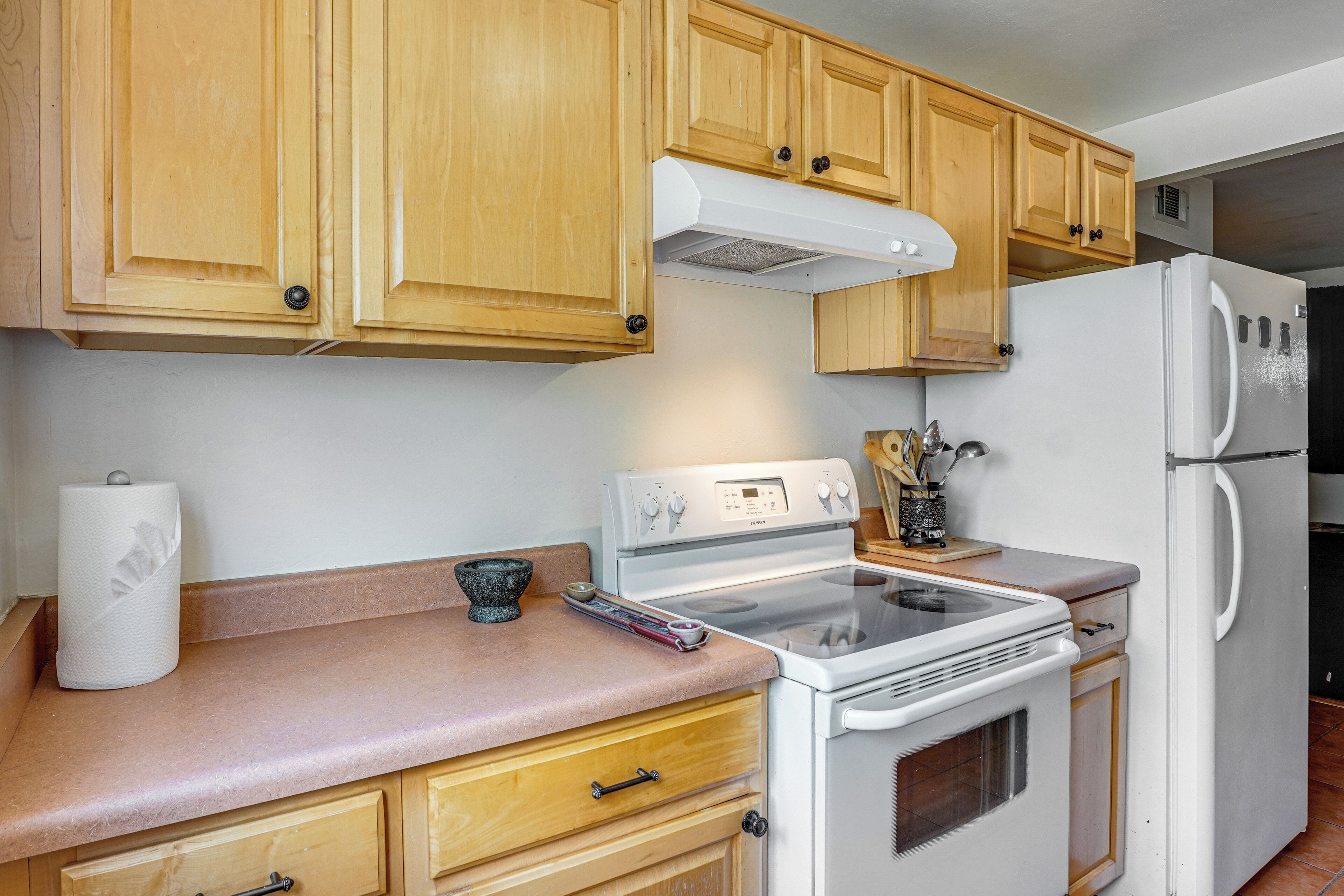 A kitchen with wooden cabinets, a white stove, and a refrigerator.