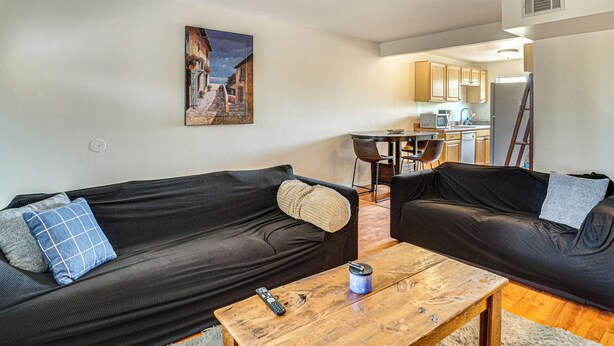 Ein Wohnzimmer mit zwei schwarzen Sofas, einem Holztisch und einem Bild an der Wand.