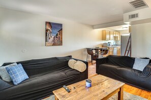 En stue med to sorte sofaer, et træsofabord og et maleri på væggen.
