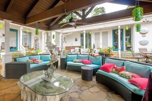 A covered outdoor seating area with wicker furniture and a glass-top table.