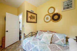 A bedroom with a bed, a door, a wall-mounted air conditioner, and a framed picture.