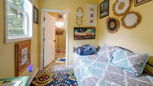 A bedroom with a bed, a window, a door, and a wall with decorative items. - Pool, Putting Green Access! Backyard Retreat (Thomaston)