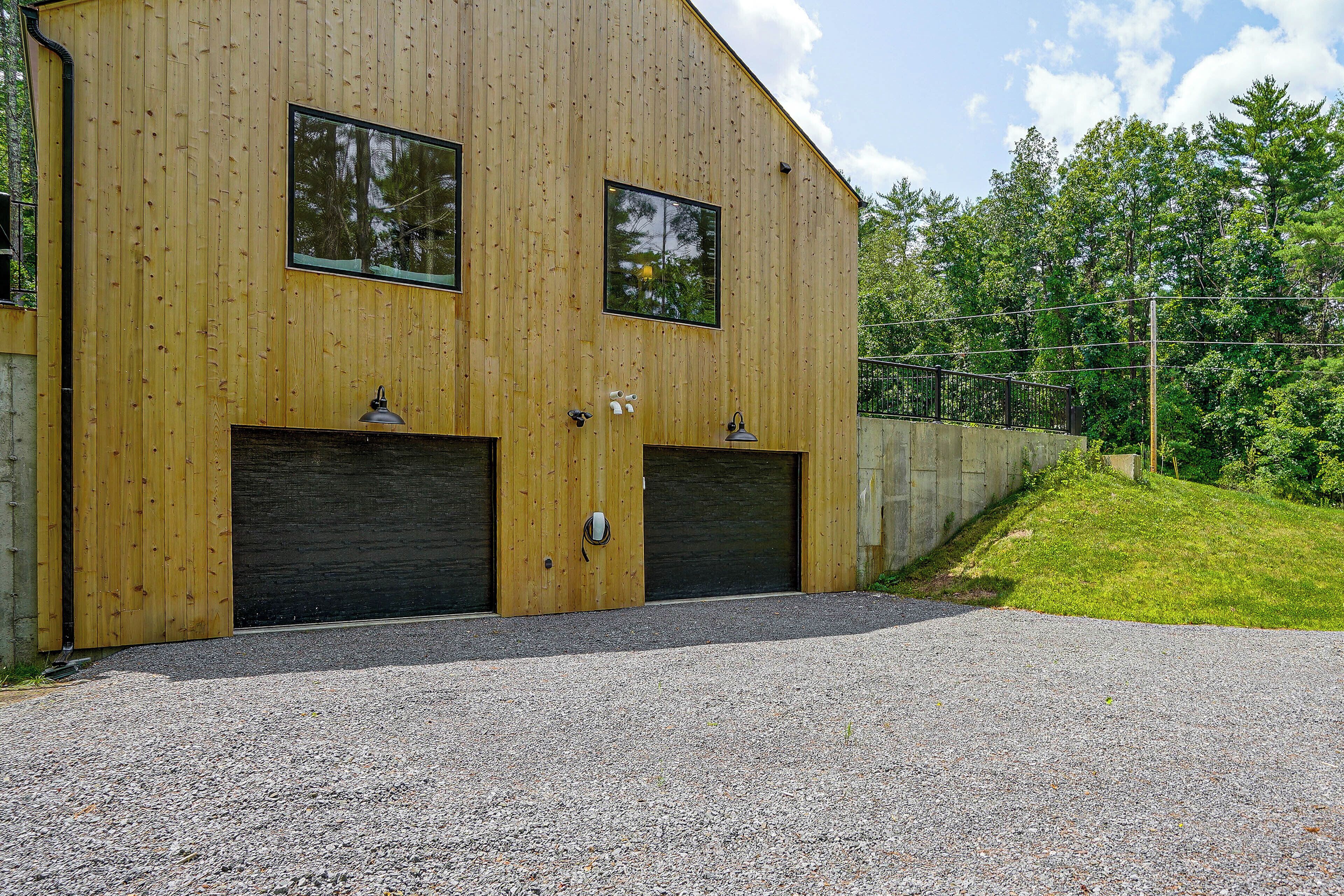 A two-story wooden building with two large garage doors and a gravel driveway.