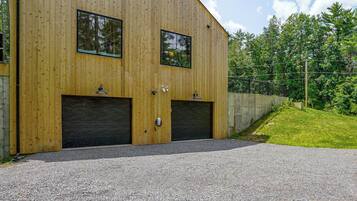 A two-story wooden building with two large garage doors and a gravel driveway.