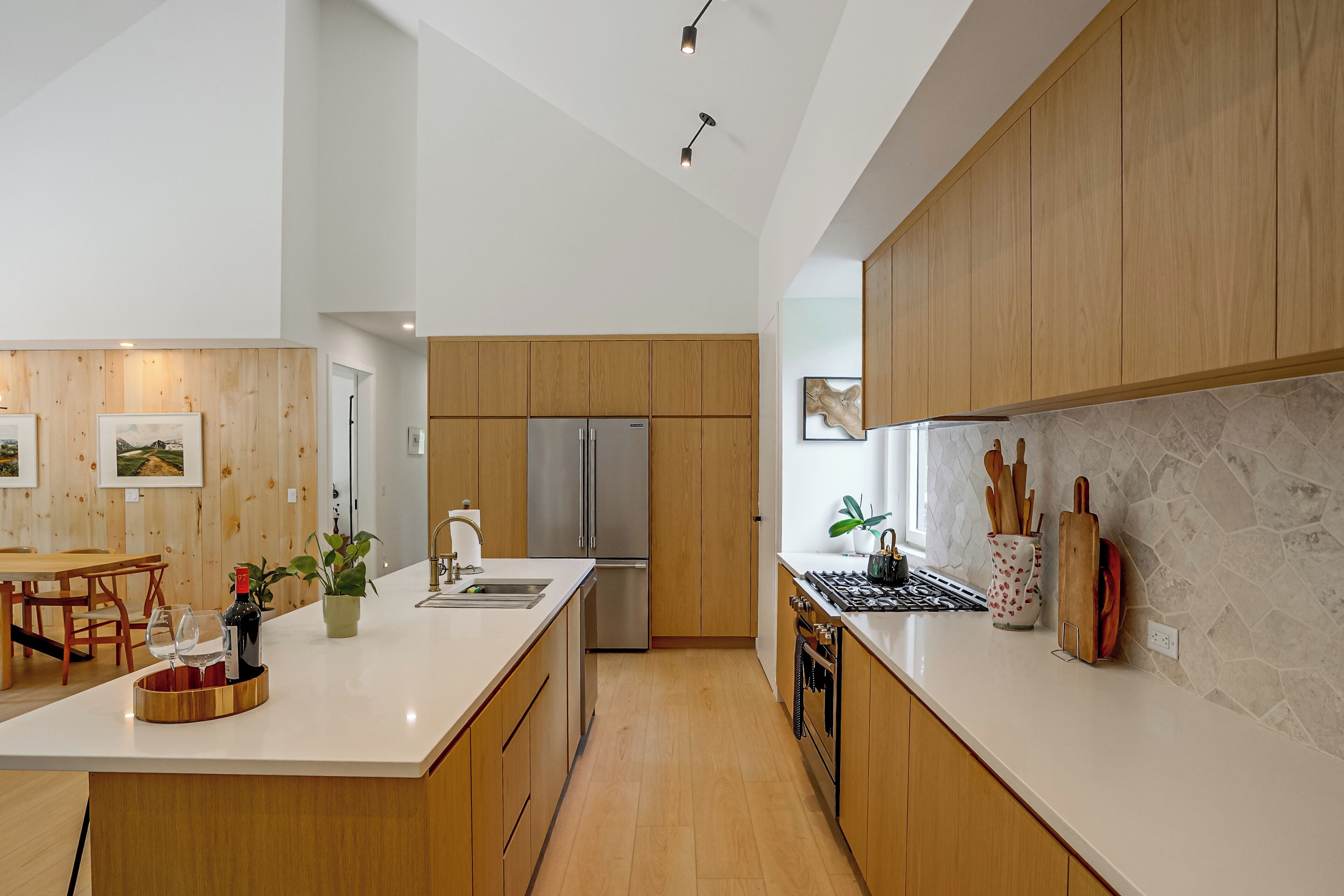 A modern kitchen with wooden cabinets, a stainless steel refrigerator, and a marble countertop.