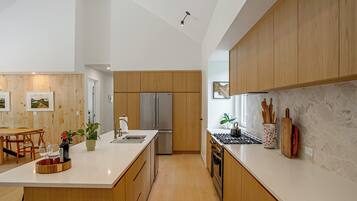 A modern kitchen with wooden cabinets, a stainless steel refrigerator, and a marble countertop.