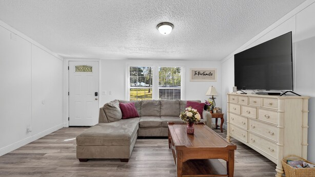 A living room with a sectional sofa, a wooden coffee table, a television, and a dresser. - 6 Mi to Rainbow Springs! Home w/ Outdoor Space (Ocala)