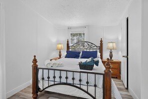 Ein ordentlich eingerichtetes Schlafzimmer mit einem Bett, zwei Nachttischen, einem Fenster und einer Tür.