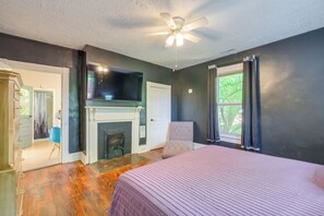 A bedroom with a bed, a ceiling fan, a fireplace, and a window with curtains. - 2 Lynchburg Units: Mansfield Manor & King's Suite! (Lynchburg)