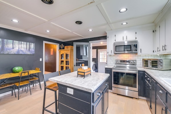 A modern kitchen with white cabinets, stainless steel appliances, and a marble countertop.