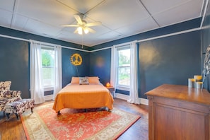 A bedroom with a bed, a nightstand, a dresser, a chair, and a window with curtains.