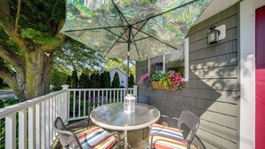 Een terras met een tafel, stoelen, een parasol en een lantaarn.