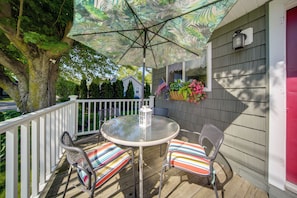 Eine Terrasse mit Tisch, Stühlen, Sonnenschirm und Laterne.