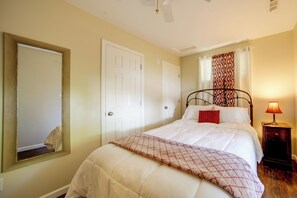 Ein Schlafzimmer mit einem Bett, einem Nachttisch, einer Lampe, einem Spiegel und zwei Türen.