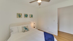 Un dormitorio con una cama, un ventilador de techo y tres obras de arte colgadas en la pared.